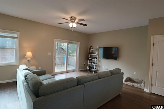 living area with a ceiling fan, dark wood finished floors, and baseboards