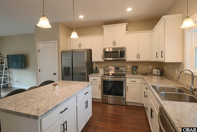 kitchen with a kitchen island, a sink, white cabinetry, hanging light fixtures, and appliances with stainless steel finishes