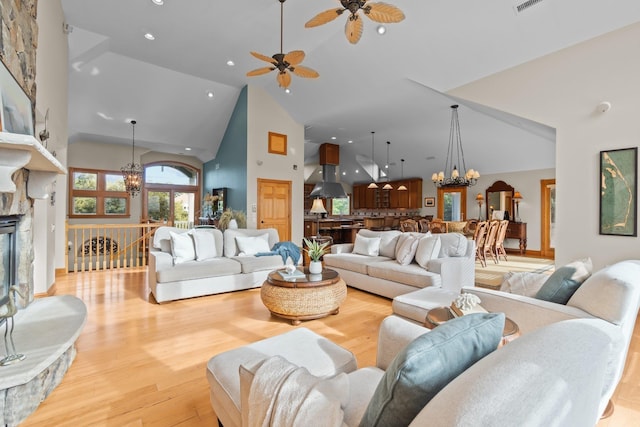 living room with light wood-style floors, visible vents, a notable chandelier, and high vaulted ceiling