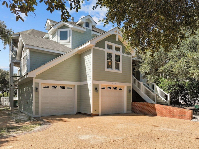 view of front of property featuring stairs, concrete driveway, and a shingled roof