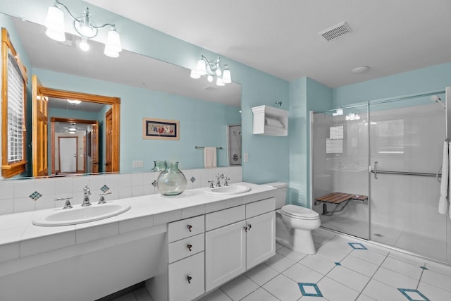 bathroom featuring toilet, double vanity, visible vents, and a sink