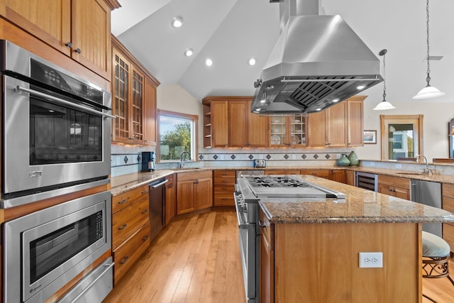 kitchen featuring island range hood, glass insert cabinets, appliances with stainless steel finishes, a breakfast bar, and hanging light fixtures