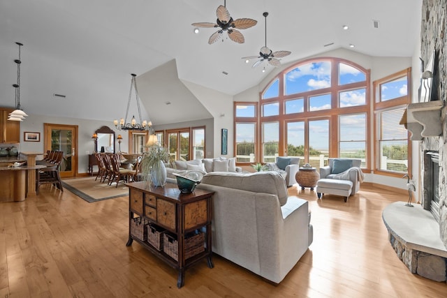 living area featuring high vaulted ceiling, a wealth of natural light, a fireplace, and light wood finished floors