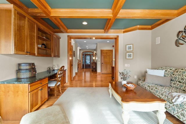 interior space with light wood-type flooring, beam ceiling, coffered ceiling, and built in desk