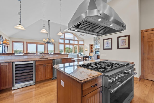 kitchen with wine cooler, brown cabinets, stainless steel appliances, a sink, and island range hood