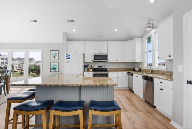 kitchen with visible vents, appliances with stainless steel finishes, white cabinetry, and lofted ceiling