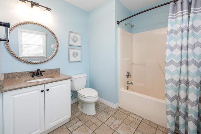 bathroom featuring stone finish flooring, baseboards, toilet, shower / bath combo with shower curtain, and vanity