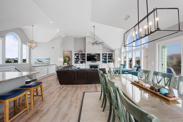 dining area with visible vents, light wood-style flooring, a fireplace, and high vaulted ceiling