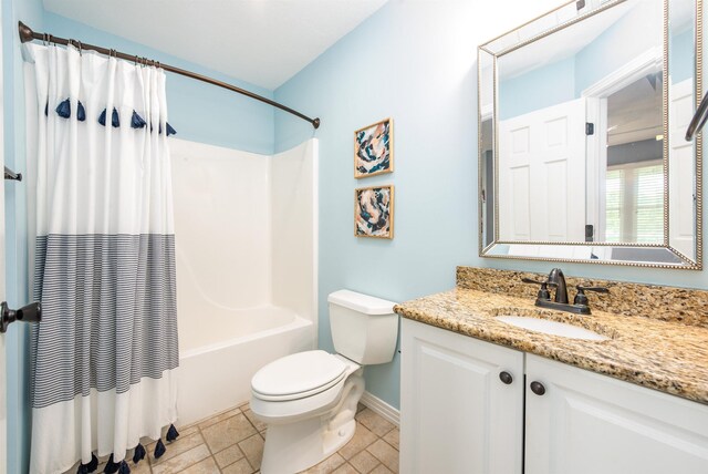 full bath featuring shower / bathtub combination with curtain, toilet, stone tile floors, baseboards, and vanity