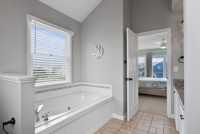 ensuite bathroom featuring a tub with jets, connected bathroom, baseboards, and lofted ceiling