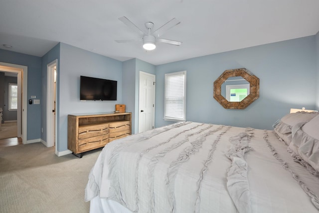 bedroom with light carpet, multiple windows, a ceiling fan, and baseboards