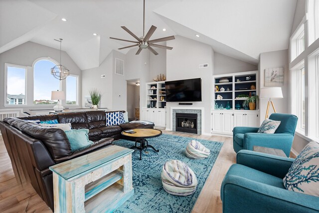 living room with visible vents, a fireplace, an inviting chandelier, light wood-style floors, and high vaulted ceiling