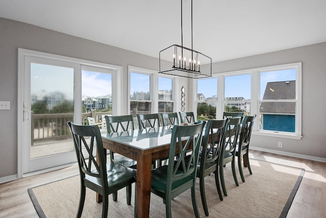 dining room featuring light wood-style floors, baseboards, and a chandelier