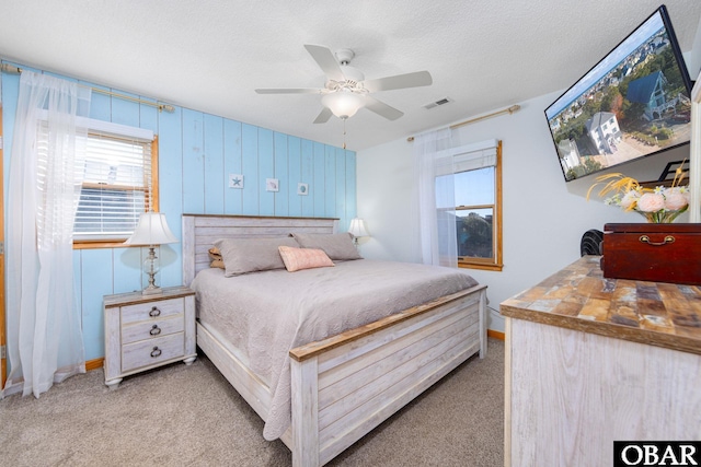 bedroom with ceiling fan, visible vents, a textured ceiling, and light colored carpet