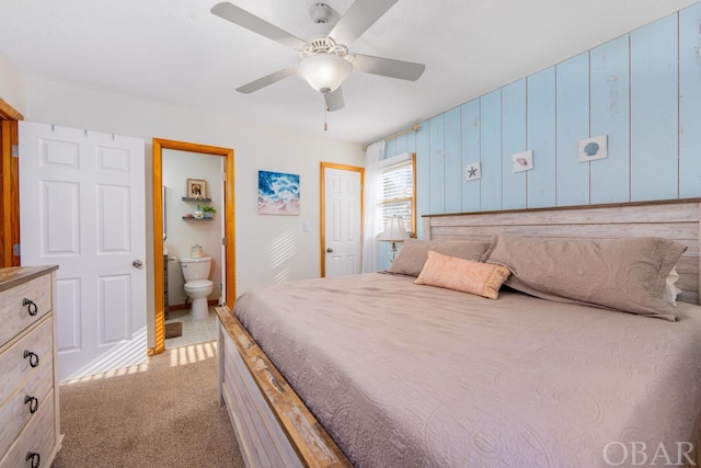 bedroom featuring a ceiling fan, light colored carpet, and ensuite bathroom