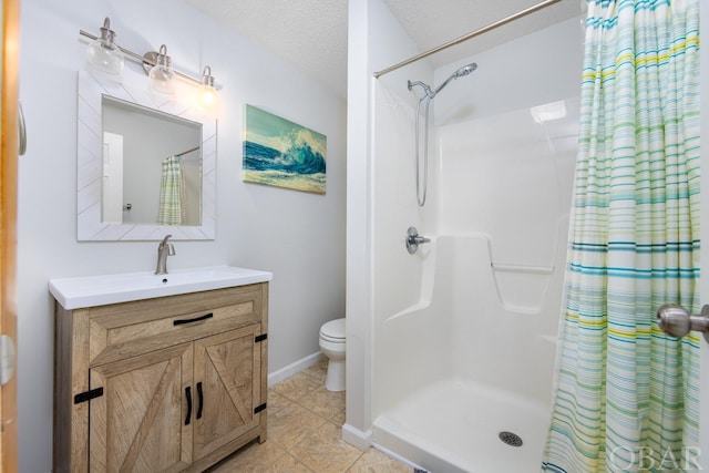 bathroom with toilet, a stall shower, vanity, a textured ceiling, and baseboards