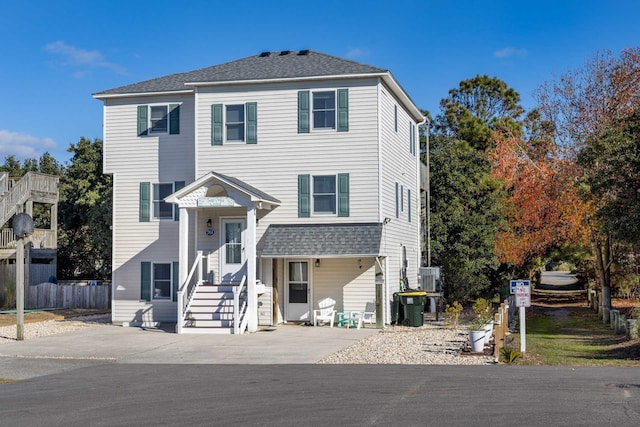 view of front of house featuring a shingled roof, fence, and cooling unit