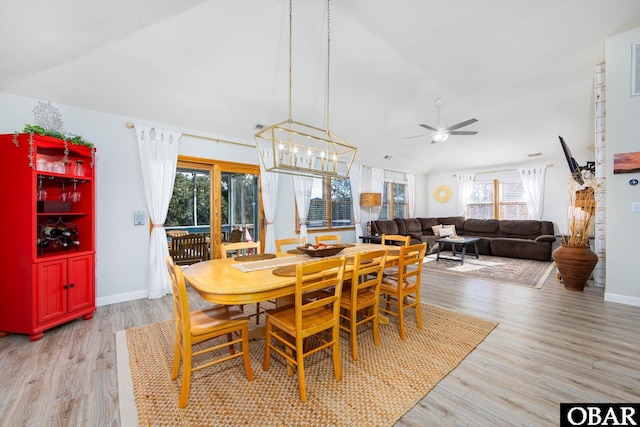 dining space featuring a ceiling fan, lofted ceiling, baseboards, and light wood finished floors