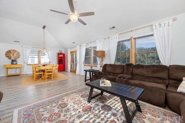 living room featuring lofted ceiling, light wood finished floors, ceiling fan, and visible vents