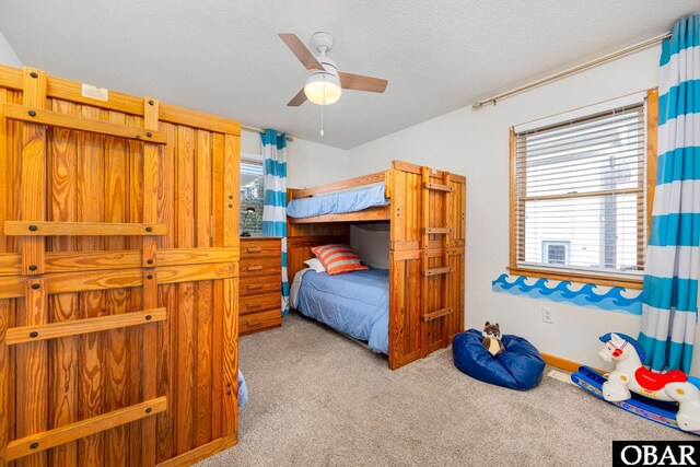 bedroom with light carpet, a ceiling fan, and a textured ceiling