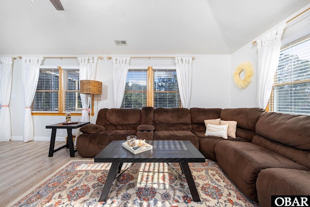 living room with lofted ceiling, a wealth of natural light, visible vents, and light wood-style floors