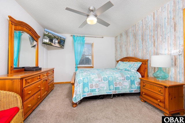 bedroom featuring a textured ceiling, ceiling fan, baseboards, and light colored carpet