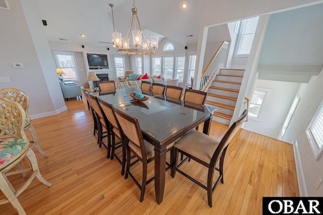 108 E Fresh Pond Dr Lot 24, Kill Devil Hills, NC 27948 - dining space featuring high vaulted ceiling, light wood-type flooring, a chandelier, stairway, and a fireplace
