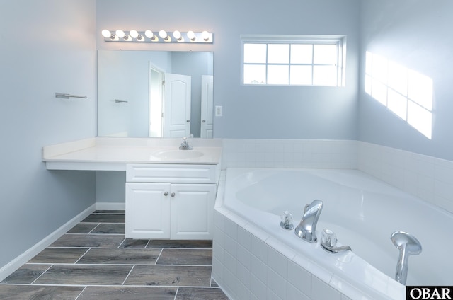 bathroom with wood tiled floor, a garden tub, vanity, and baseboards