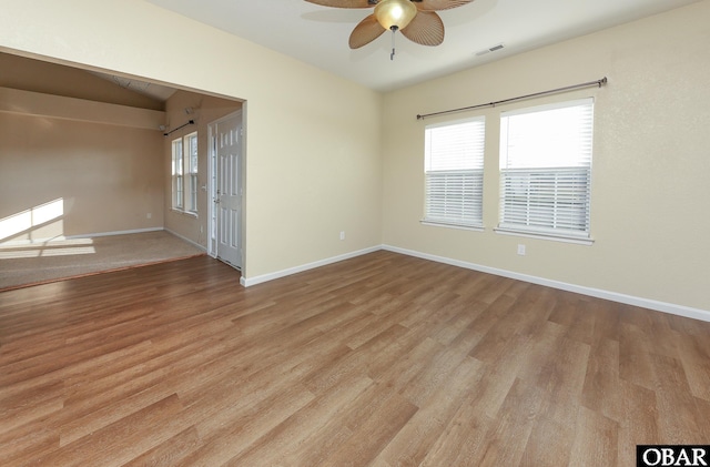 empty room featuring light wood finished floors, visible vents, baseboards, and ceiling fan