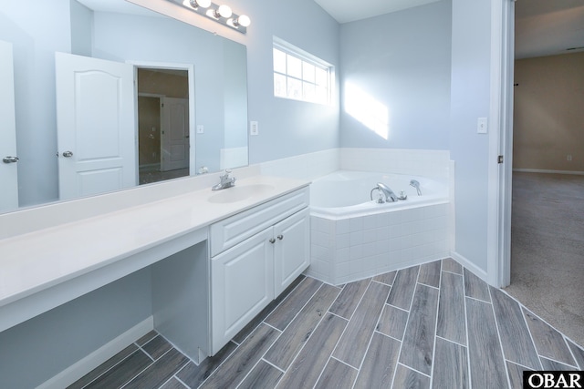 full bathroom featuring wood finish floors, a garden tub, vanity, and baseboards