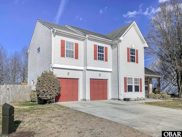 traditional home with fence, driveway, and an attached garage