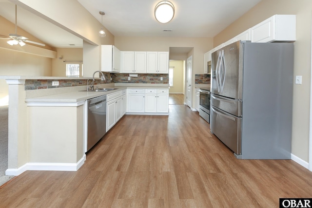 kitchen with stainless steel appliances, light countertops, white cabinetry, a sink, and a peninsula