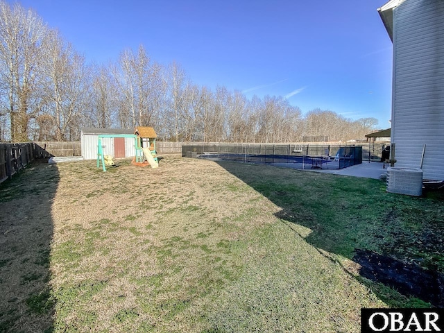 view of yard featuring a playground, a storage shed, a patio area, a fenced backyard, and an outdoor structure