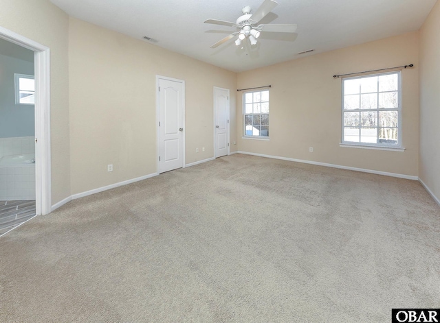 spare room with ceiling fan, visible vents, baseboards, and light colored carpet