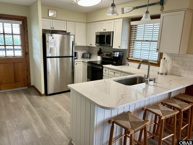 2429 S Virginia Dare Trl Unit 4, Nags Head, NC 27959 - kitchen with stainless steel appliances, a peninsula, light stone countertops, and white cabinetry