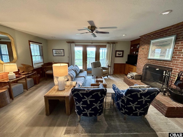 2429 S Virginia Dare Trl Unit 4, Nags Head, NC 27959 - living room featuring wood finished floors, a fireplace, ceiling fan, a wainscoted wall, and a textured ceiling