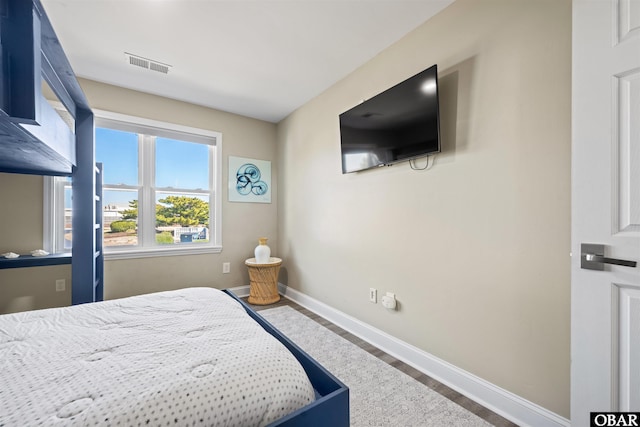 bedroom featuring visible vents, baseboards, and wood finished floors