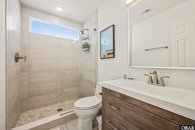 full bathroom with toilet, visible vents, a tile shower, and vanity