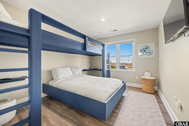 bedroom with dark wood-style floors, visible vents, and baseboards