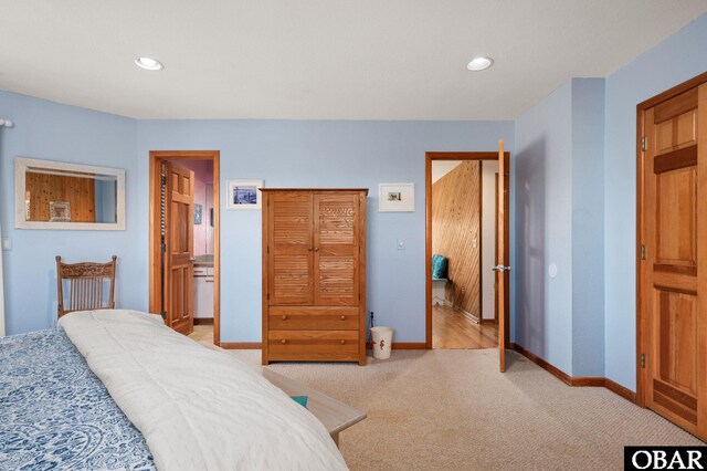 bedroom with recessed lighting, baseboards, light colored carpet, and ensuite bath