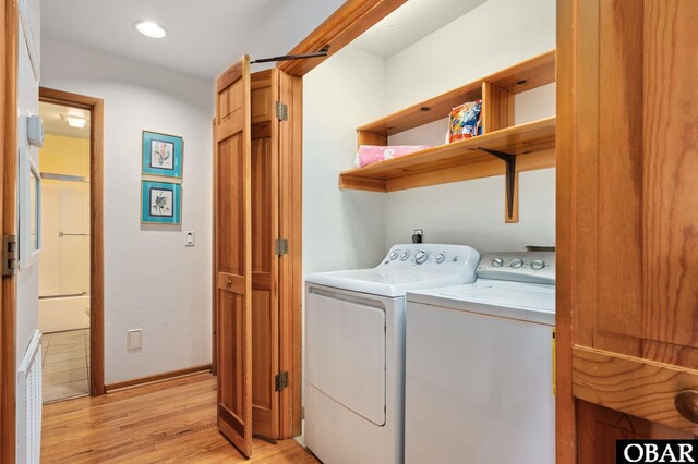 laundry area featuring washer and clothes dryer, laundry area, baseboards, and light wood-style floors