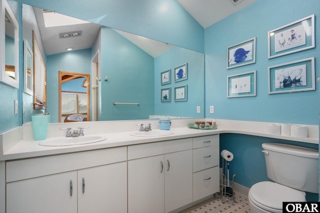 ensuite bathroom featuring vaulted ceiling, toilet, ensuite bathroom, and a sink