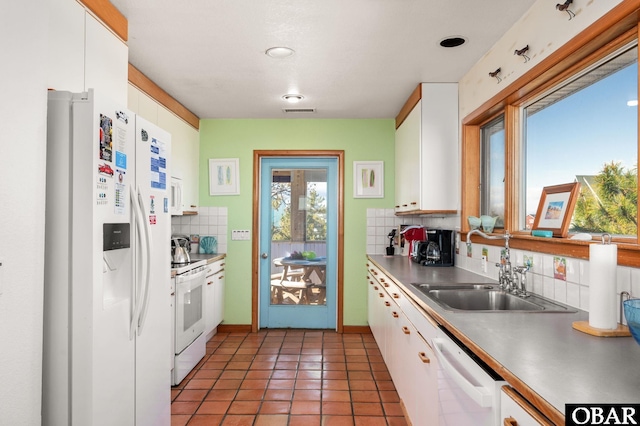 kitchen with a sink, backsplash, white cabinetry, white appliances, and light tile patterned flooring