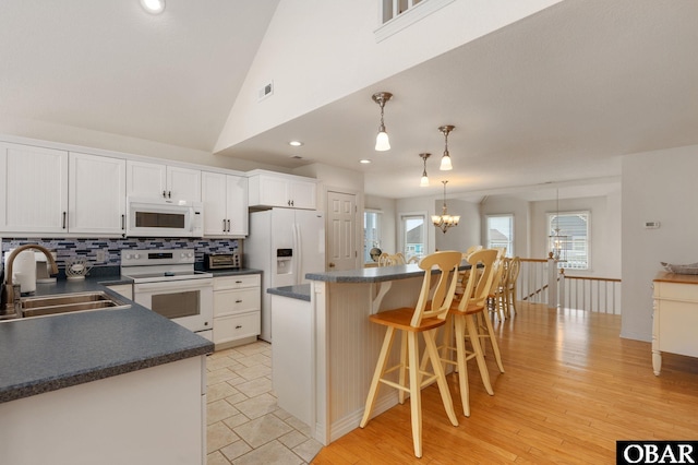 716 Moongate Ln Lot 51, Corolla, NC 27927 - kitchen with a sink, white appliances, dark countertops, decorative backsplash, and a breakfast bar area