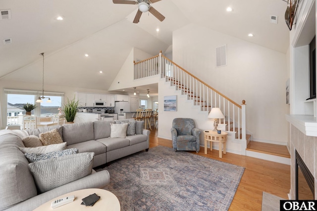 716 Moongate Ln Lot 51, Corolla, NC 27927 - living room featuring stairs, high vaulted ceiling, light wood-style floors, a ceiling fan, and healthy amount of natural light