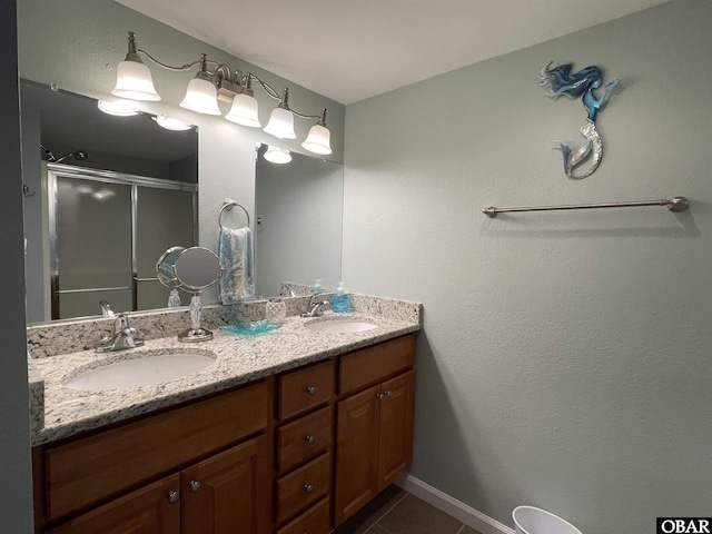 bathroom featuring double vanity, tile patterned floors, a shower stall, and a sink