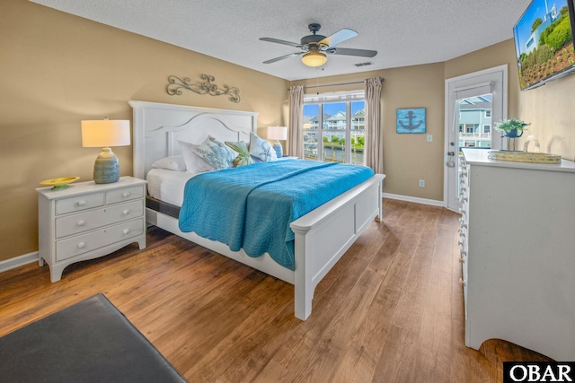 612 Pirates Way Unit # 612B, Manteo, NC 27954 - bedroom with light wood-style flooring, access to outside, baseboards, a textured ceiling, and ceiling fan