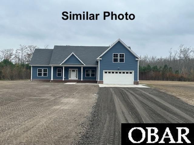 view of front of property featuring a garage and dirt driveway