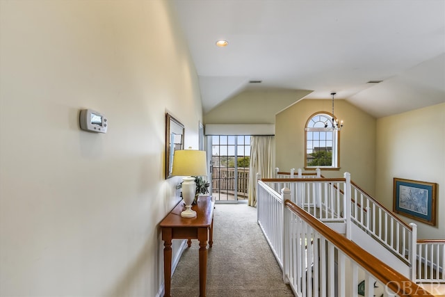 corridor with visible vents, lofted ceiling, an upstairs landing, carpet floors, and a notable chandelier