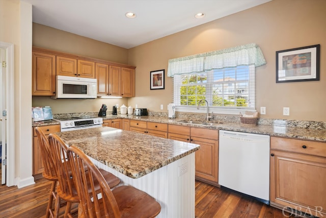 kitchen with white appliances, a kitchen island, a sink, and light stone countertops